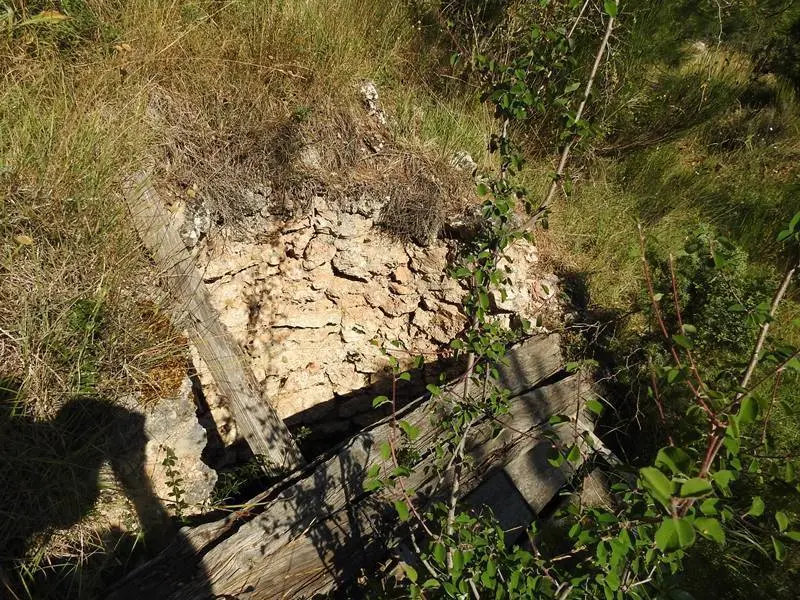 Un pozo antiguo junto a una edificaci&oacute;n en ruinas